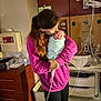 woman, baby, newborn, hospital, medical_equipment, blanket, pink_hoodie, love, affection, holding, indoor, face, person, sleeping_baby, cabinet, monitor, tubing, hand, care, room