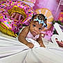 Kaira is registered to the contest to win money with this photo: baby, child, braids, blue_bows, pink_balloon, donut_balloon, white_sheet, indoor, curious, decorations, celebration, portrait, infant, face, cute, person, closeup, colorful, festive, smiling