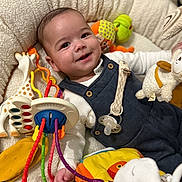 Victor participe au concours pour gagner de l'argent avec cette photo : baby, smiling, toy, giraffe_toy, pacifier, plush_toy, baby_nest, infant, colorful, cute, child, white_shirt, blue_overall, hand, face, happy, lying_down, soft_texture, bright, indoor