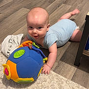 Lorenzo a rejoint le concours — aidez-le/la à gagner de superbes lots ! baby, blue_clothing, carpet, child, colorful, crawling, face, floor, furniture, hand, head, home, indoor, infant, onesie, plush_toy, rug, toy, vacuum_cleaner, wooden_floor