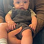 baby, child, person, face, hands, legs, socks, overalls, striped_shirt, tattoo, arm, holding, indoor, closeup, cute, expression, skin, casual_clothing, infant, portrait