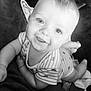 baby, child, smiling, face, eyes, onesie, striped_clothing, infant, cute, lying_down, soft_surface, cheeky_smile, monochrome, black_and_white, close_up, happy, small_toys, foot, hand, indoors
