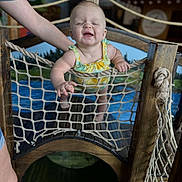 Roselie joined the competition — help win amazing prizes! baby, child, smiling, rope_net, playground, wooden_structure, indoor, person, clothing, happy, support, hand, play_area, netting, infant, fun, childcare, lemon_pattern, arm, laughing