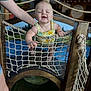 baby, child, smiling, rope_net, playground, wooden_structure, indoor, person, clothing, happy, support, hand, play_area, netting, infant, fun, childcare, lemon_pattern, arm, laughing