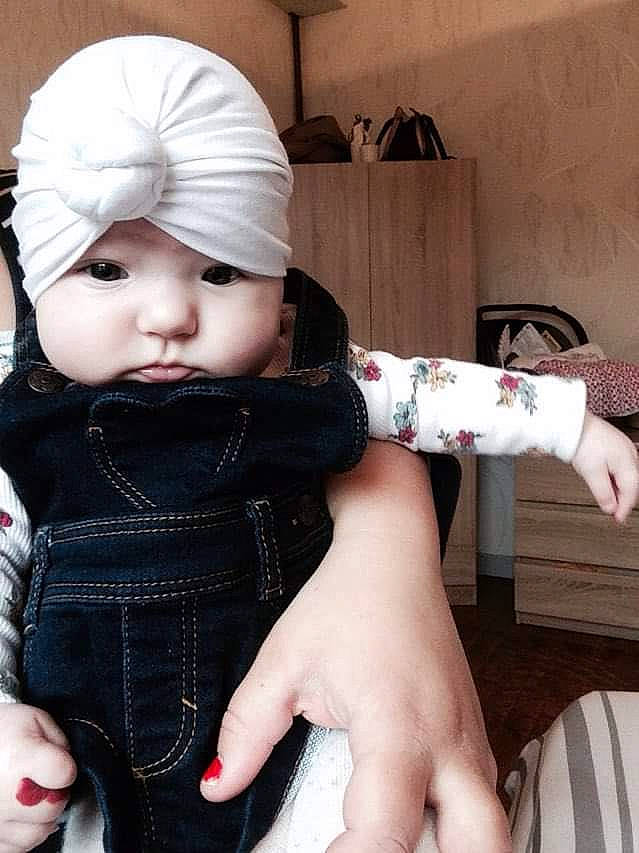 Paola a rejoint le concours — aidez-le/la à gagner de superbes lots ! baby, baby_toddler_clothing, cap, cheek, chin, dress, eye, eyelash, finger, gesture, hand, head, headwear, human_body, joint, lip, outerwear, person, pink, skin