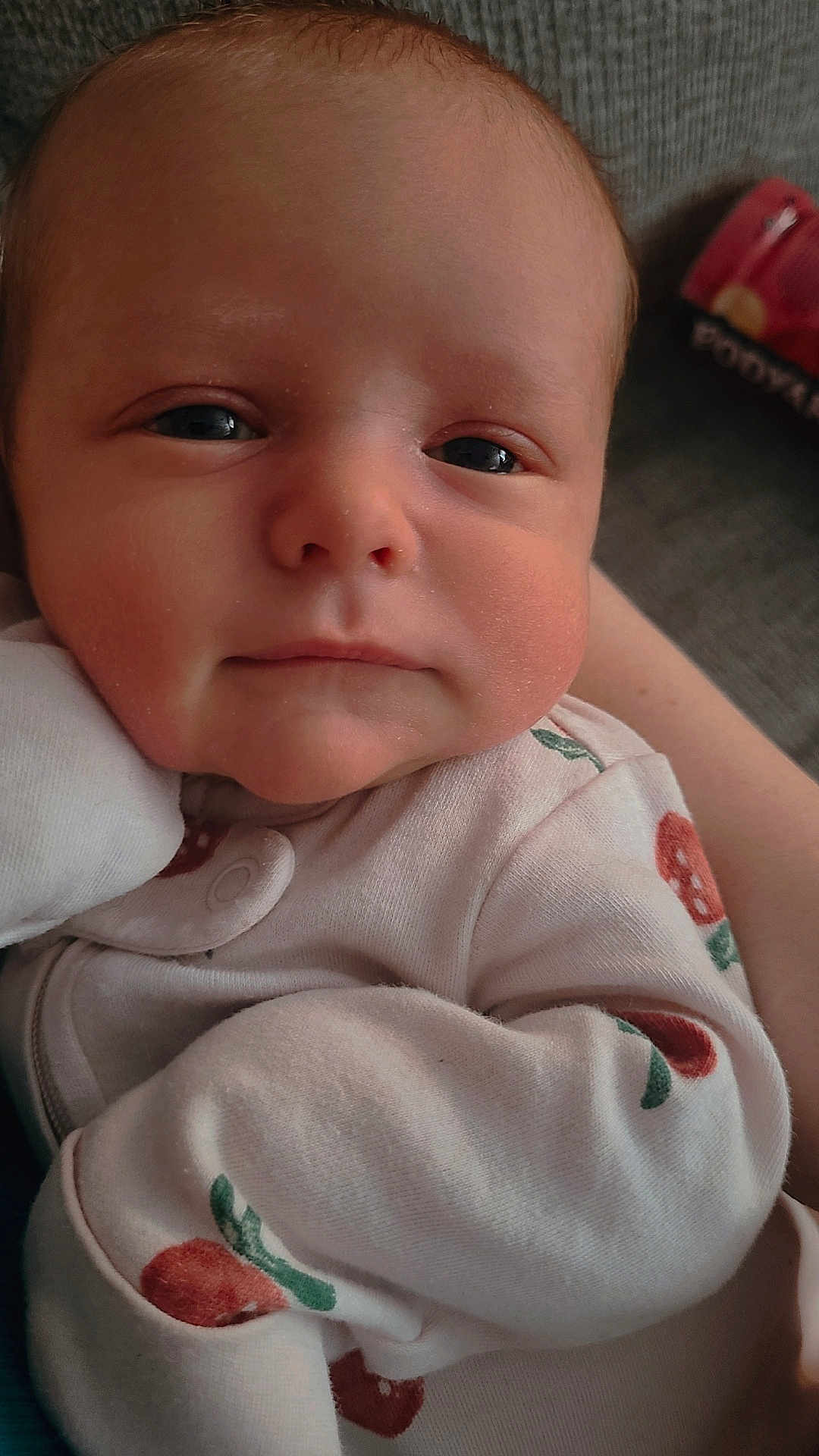 Amira is registered to the contest to win money with this photo: baby, infant, face, close_up, sleepy, clothing, patterned_outfit, skin, head, eyes, person, cute, newborn, resting, indoors, soft_light, portrait, young_child, baby_clothes, hand