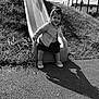 Inaya participe au concours pour gagner de l'argent avec cette photo : toddler, child, smiling, slide, playground, outdoor, grass, sunlight, shadow, fence, happiness, skirt, cardigan, shoes, pavement, nature, play, young_child, black_and_white, portrait