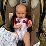 baby, infant, car_seat, blanket, outdoor, grass, clothing, smile, face, person, seat_belt, head, hand, legs, fabric, cute, happy, child, child_in_car_seat, baby_clothes