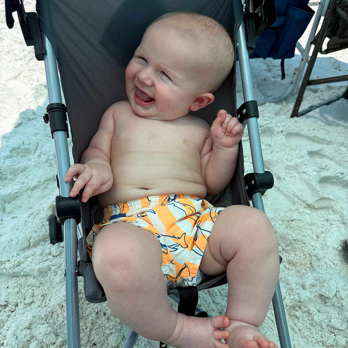 Wylder joined the competition — help win amazing prizes! baby, child, smiling, stroller, beach, sand, sunlight, summer, happy, infant, bare_chest, shorts, outdoor, relaxing, cute, person, legs, feet, vacation, playful