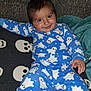 Rueben is registered to the contest to win money with this photo: baby, blanket, blue_clothing, child, comfort, cozy, cute, face, ghost_pattern, happy, indoor, pajamas, person, playful, portrait, sitting, skull_blanket, smiling, toddler, young_child