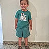 Addiel joined the competition — help win amazing prizes! child, boy, toddler, smiling, standing, portrait, indoor, home, green_outfit, shorts, t_shirt, sandals, cartoon_dogs, clothing, wall, floor, doorway, daylight, happy, full_body