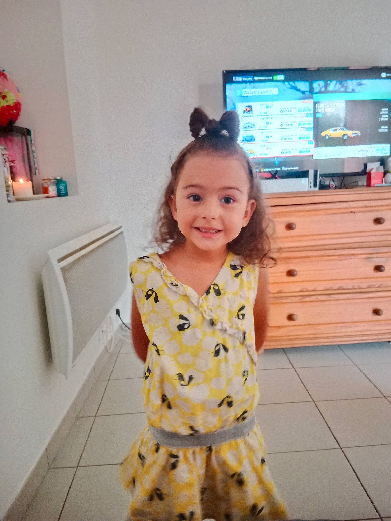 Sophia participe au concours pour gagner de l'argent avec cette photo : baby_toddler_clothing, cabinetry, chest_of_drawers, child, drawer, entertainment_center, event, flooring, fun, happy, hardwood, home_appliance, joy, pattern, person, room, sleeve, smile, television, television_set