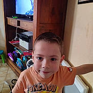 Enoha participe au concours pour gagner de l'argent avec cette photo : backpack, boy, cabinet, casual, child, face, floor, furniture, hair, home, indoor, person, pokemon, portrait, radiator, room, smile, television, toy, tshirt