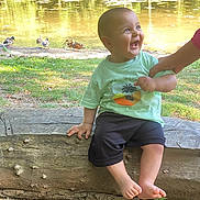 Jad Erradi a rejoint le concours — aidez-le/la à gagner de superbes lots ! baby, child, smiling, laughing, pond, ducks, water, grass, tree, log, outdoor, nature, summer, sunlight, hand, person, clothing, shorts, tshirt, barefoot