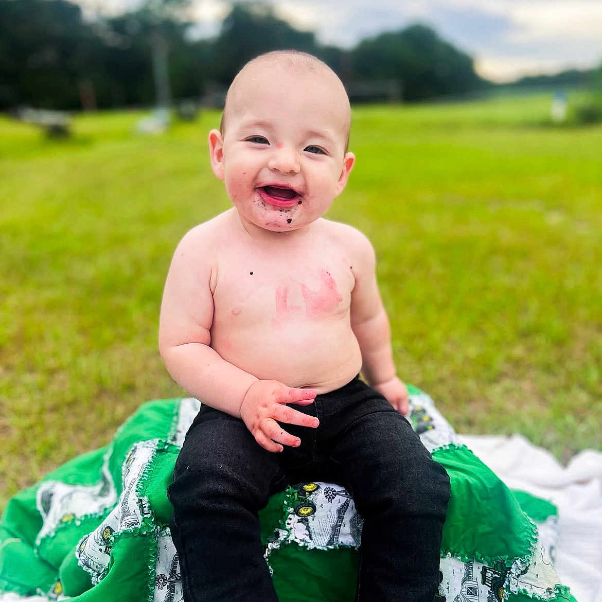 Creeden joined the competition — help win amazing prizes! baby, blanket, casual, child, daylight, face, field, footwear, grass, green, happy, infant, nature, outdoor, pants, shirtless, sitting, smiling, trees, young