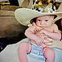 baby, infant, hat, cowboy_hat, feathers, diaper, person, hand, nail_polish, furniture, couch, living_room, skin, legs, arms, cute, portrait, indoor, holding, seated