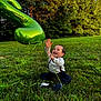 Jayden is registered to the contest to win money with this photo: toddler, child, balloon, green_balloon, number_two, grass, outdoor, nature, smiling, happy, sitting, sunlight, trees, playful, celebration, casual_clothing, suspenders, shoes, joyful, daytime