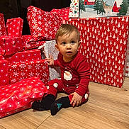Ezio a rejoint le concours — aidez-le/la à gagner de superbes lots ! celebration, child, christmas, curious, cute, face, festive, floor, gifts, holiday, holiday_season, indoors, pajamas, presents, red_clothing, sitting, toddler, wooden_floor, wrapped_gifts, young_child