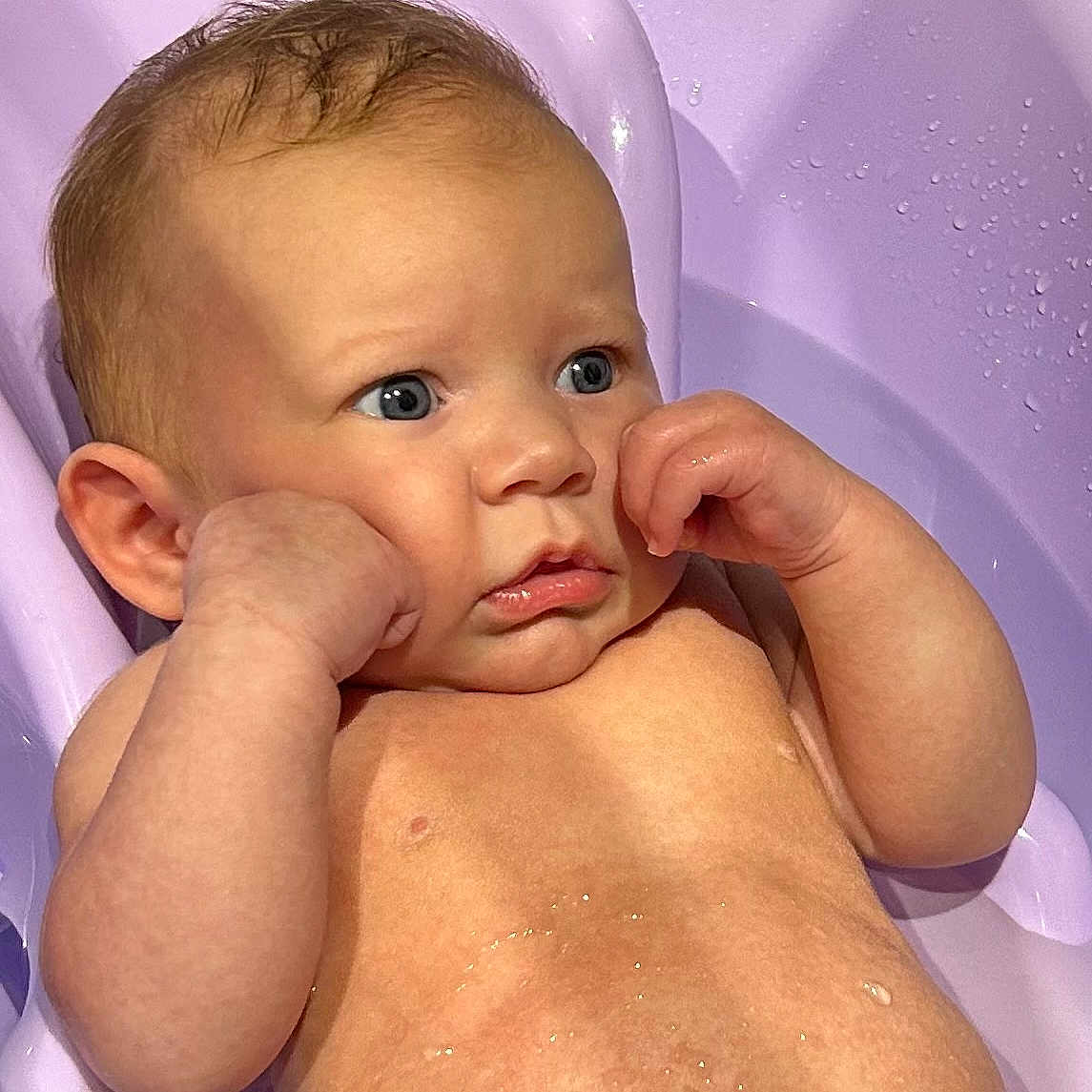 Ezio participe au concours pour gagner de l'argent avec cette photo : baby, bath, bath_time, bathtub, blue_eyes, child, closeup, curly_hair, cute, expression, face, hands, indoors, infant, person, purple_bathtub, skin, toddler, water, wet_skin