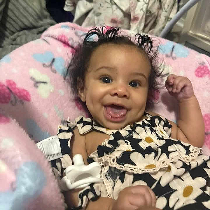 Leiloni Braziel joined the competition — help win amazing prizes! baby, black_and_white, blanket, butterflies, child, closeup, clothing, cozy, curly_hair, cute, cute_outfit, face, floral_pattern, happy, indoors, infant, lying_down, person, smiling, soft_texture