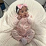baby, infant, pink_clothing, headband, bow, blanket, soft_texture, cute, sitting, indoor, child, person, portrait, cozy, small_hands, facial_expression, strawberry_pattern, footwear, white_blanket, curious