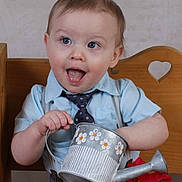 Liam is registered to the contest to win money with this photo: toddler, child, watering_can, blue_shirt, tie, suspenders, wooden_bench, heart_cutout, autumn_leaves, red_leaf, yellow_leaf, happy, smiling, indoors, portrait, cute, playful, expression, person, shorts
