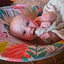 baby, infant, blanket, baby_seat, colorful, indoor, floor, toy, furniture, wood_floor, face, person, child, cute, soft_toy, comfort, home, portrait, expression, holding