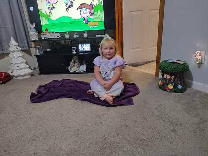 Karissa is registered to the contest to win money with this photo: child, curtain, display_device, door, electronic_device, event, floor, flooring, fun, hardwood, human_leg, knee, person, play, room, sitting, television, television_set, toddler, toy