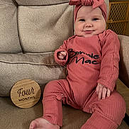 Bonnie joined the competition — help win amazing prizes! baby, infant, four_months, wooden_sign, headband, bow, pink_outfit, onesie, smile, chubby_cheeks, arm, leg, foot, chair, patterned_fabric, baby_month_marker, sitting, portrait, indoor, baby_gate