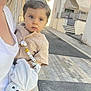 toddler, child, baby, blue_eyes, pacifier_clip, soft_toy, urban, street, daylight, adult, holding, curious, clothing, sidewalk, buildings, outdoor, person, face, cute, portrait