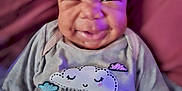 Amira is registered to the contest to win money with this photo: baby, infant, smiling, face, clothing, pillow, purple_light, indoor, cute, happy, portrait, sitting, child, soft_toys, cozy, dream, long_sleeve, expression, closeup, candid