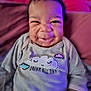 baby, infant, smiling, face, clothing, pillow, purple_light, indoor, cute, happy, portrait, sitting, child, soft_toys, cozy, dream, long_sleeve, expression, closeup, candid