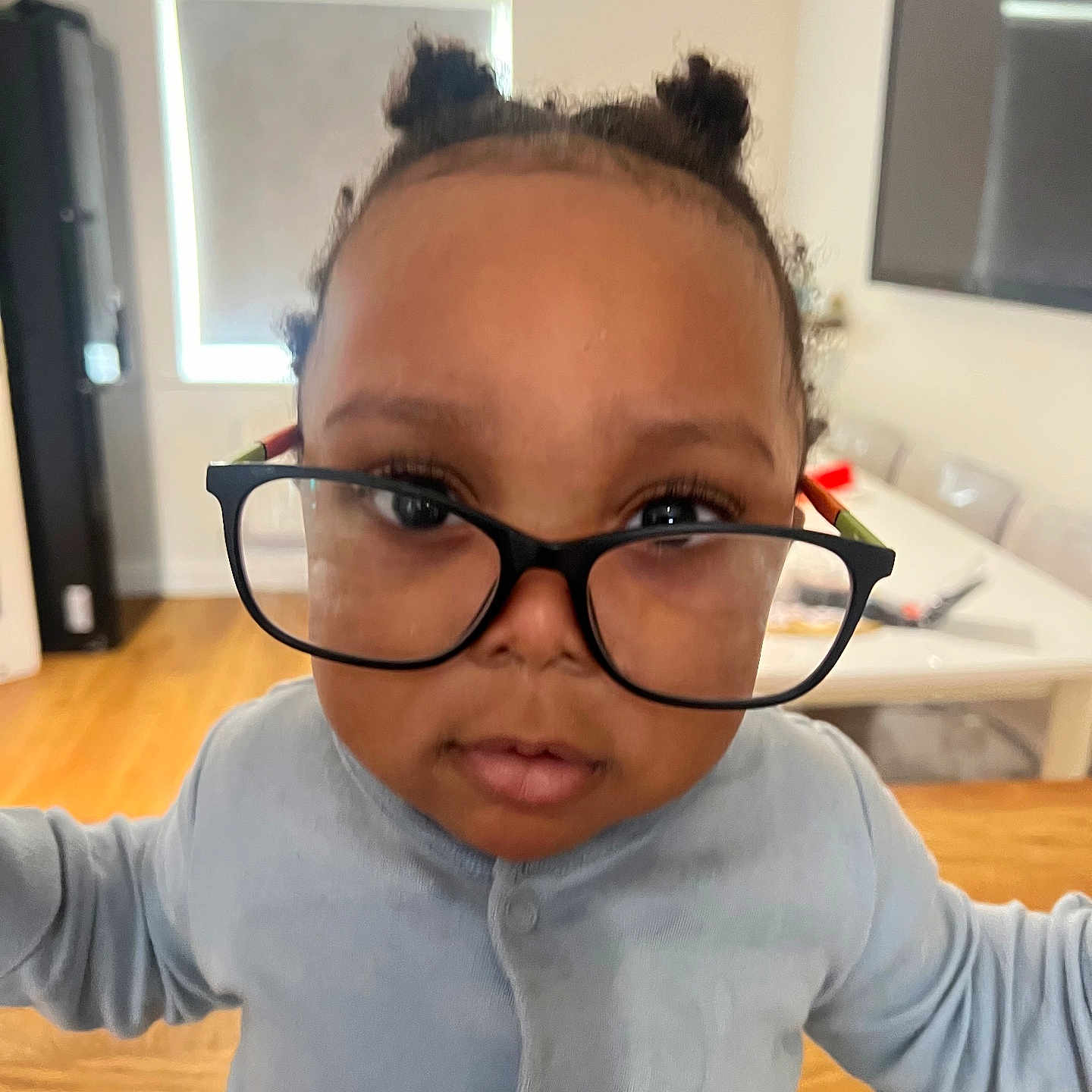 Oziah Omoniyi joined the competition — help win amazing prizes! casual_clothing, chair, child, curious, expression, face, floor, glasses, hair_buns, home, indoors, light, long_sleeve, magnified_eyes, person, portrait, table, toddler, window, young_child