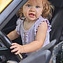 Aubrey joined the competition — help win amazing prizes! toddler, child, car, steering_wheel, curly_hair, blue_eyes, purple_clothing, sleeveless_top, hand, face, expression, indoor, seat, window, closeup, portrait, young_child, cute, playing, curious
