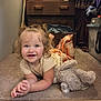 Aubrey is registered to the contest to win money with this photo: child, toddler, smiling, curly_hair, plush_toy, carpet, indoor, dresser, storage_bin, clothing, person, cute, happy, baby, floor, toy, room, casual, home, portrait