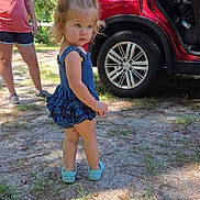 Aubrey joined the competition — help win amazing prizes! blue_dress, car, casual_clothing, child, daytime, dirt, grass, nature, open_car_door, outdoor, person, red_car, serious_expression, shadow, shoes, standing, sunlight, toddler, trees, woman