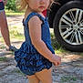 toddler, child, outdoor, blue_clothing, pigtails, red_car, grass, shoes, person, summer, sunlight, side_view, cute, nature, vehicle, young_child, casual_wear, serious_expression, bare_legs, daytime