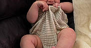 Beau is registered to the contest to win money with this photo: baby, infant, couch, leather, blanket, cloth, smiling, cute, chubby, playful, sitting, indoors, skin, foot, hand, face, expression, cozy, texture, person