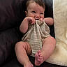 baby, infant, couch, leather, blanket, cloth, smiling, cute, chubby, playful, sitting, indoors, skin, foot, hand, face, expression, cozy, texture, person