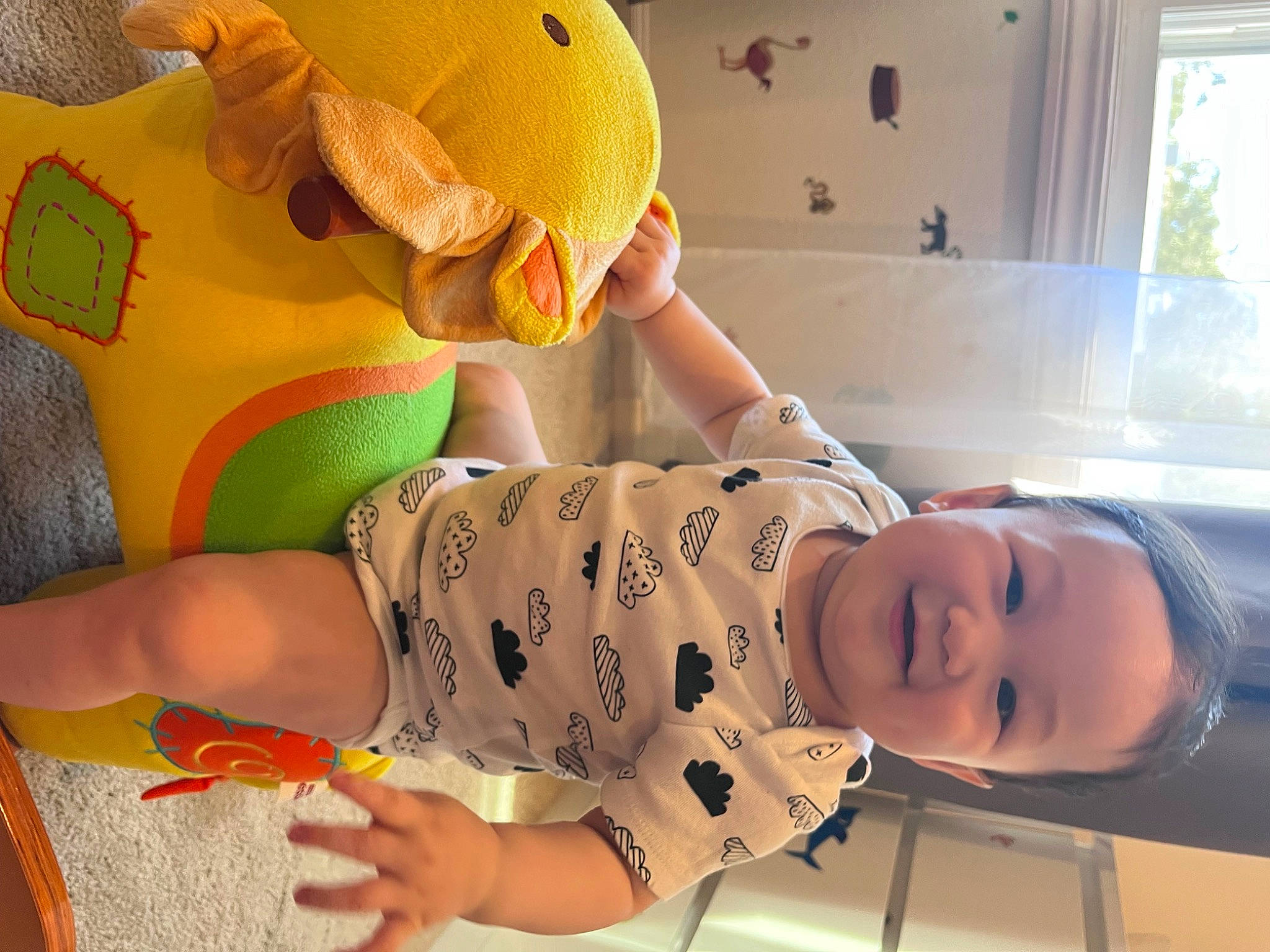Emma is registered to the contest to win money with this photo: baby, baby_products, baby_toddler_clothing, child, flooring, fun, happy, human_leg, nightwear, orange, pattern, person, play, room, sleeve, smile, stuffed_toy, thigh, toddler, window