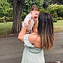 Milan is registered to the contest to win money with this photo: baby, child, dress, family, fun, grass, greenery, happy, holding, joy, laughing, nature, outdoor, park, person, road, smile, tattoo, tree, woman