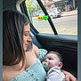 affection, baby, buildings, car_interior, cars, child, daylight, emotion, green_dress, holding, love, pacifier, parenting, person, road, seat, side_profile, street, window, woman