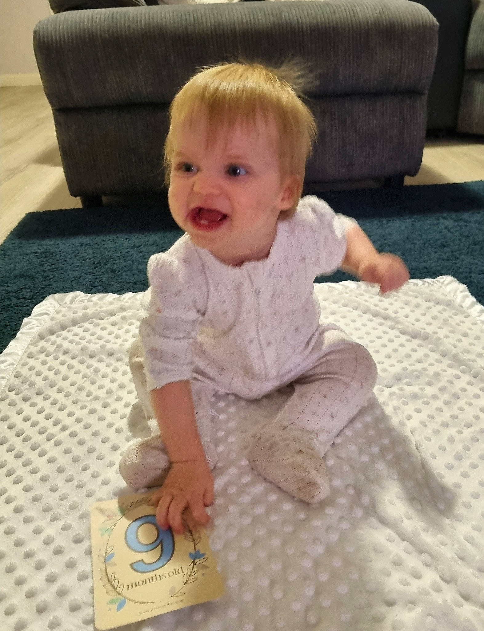 Hallee is registered to the contest to win money with this photo: baby, baby_toddler_clothing, carpet, child, comfort, couch, facial_expression, floor, flooring, human, linens, living_room, pattern, person, room, sitting, skin, sleeve, smile, toddler