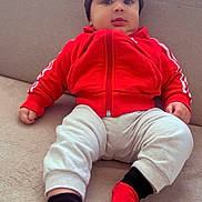 Alseny Camara participe au concours pour gagner de l'argent avec cette photo : baby, child, infant, red_jacket, hat, socks, couch, indoor, casual_clothing, cute, person, seated, relaxed, home, portrait, looking_at_camera, comfortable, young_child, fashion, sporty