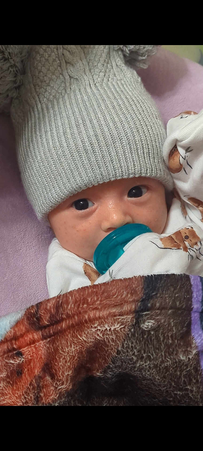 Jesus joined the competition — help win amazing prizes! baby, infant, pacifier, knitted_hat, blanket, sleepwear, closeup, face, eyes, cute, child, indoors, cozy, soft_texture, wearing, portrait, warm, resting, newborn, comfort