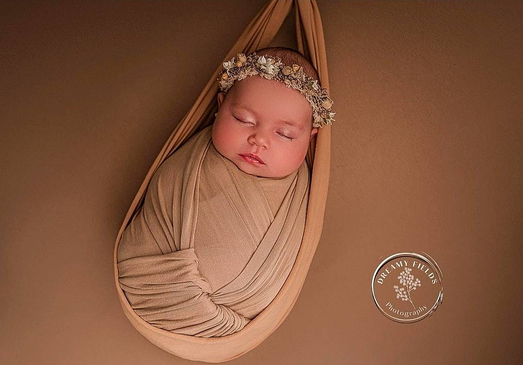 Olivia is registered to the contest to win money with this photo: arm, baby, bridal_accessory, chin, circle, costume_hat, crown, eye, eyelash, fashion_accessory, flash_photography, hair_accessory, hand, head, headband, headgear, headpiece, headwear, jewellery, person