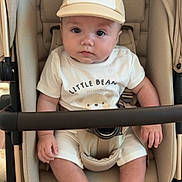 Ezra is registered to the contest to win money with this photo: baby, baby_accessories, baby_clothing, beige, cap, child, clothing, cute, eyes, face, footwear, hands, hat, indoor, infant, legs, neutral_colors, portrait, sitting, stroller