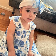 Amelia is registered to the contest to win money with this photo: child, toddler, girl, dress, floral_pattern, headband, bow, indoor, couch, cushion, floor, wood_floor, person, cute, young, sitting, curious, pink_skin, home, soft_lighting