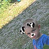 child, boy, outdoor, grass, playground, toy, face_filter, dog_ears, dog_nose, blue_shirt, short_hair, sitting, curious, play, daylight, nature, cute, young, person, casual