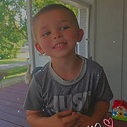 Easton is registered to the contest to win money with this photo: child, boy, smiling, porch, outdoor, tshirt, shorts, sparkles, handwritten_text, heart, wooden_floor, greenery, daylight, happy, casual_clothing, person, young, cute, summer, playful